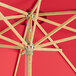 A Lancaster Table & Seating bamboo umbrella with a red canopy.