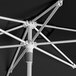 A close-up of a black Lancaster Table & Seating round umbrella with a silver aluminum lift.