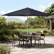 A navy Lancaster Table & Seating umbrella over a table and chairs on a patio.