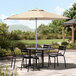 A round sand umbrella over a table with chairs on a patio.