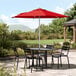 A Lancaster Table & Seating round table and chairs with a red umbrella.