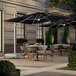 A Lancaster Table & Seating black cantilever umbrella with lights on a table outside under umbrellas.