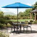 A table and chairs under a blue Lancaster Table & Seating umbrella.