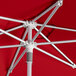 A close up of a red Lancaster Table & Seating round umbrella with a silver pole.