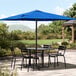 A black table with chairs under a blue Lancaster Table & Seating umbrella.