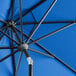 A close up of a Lancaster Table & Seating cobalt blue umbrella with black metal poles.