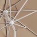 A close up of a white Lancaster Table & Seating round umbrella with a tan base.