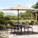 A Lancaster Table & Seating black umbrella shading a table and chairs on a stone patio.