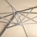 The metal structure of a Lancaster Table & Seating square umbrella with a beige canopy.