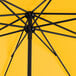 A close up of a Lancaster Table & Seating round canary yellow umbrella with black poles.