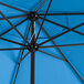 A close up of a blue Lancaster Table & Seating umbrella with black poles.