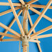 A Lancaster Table & Seating bamboo umbrella with a blue canopy.