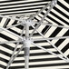 A close up of a Lancaster Table & Seating black and white striped umbrella with a white pole.