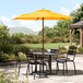 A Lancaster Table & Seating yellow woodgrain aluminum umbrella on a patio table.