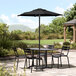 A black table and chairs on a patio under a black umbrella.