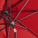 A close up of a Lancaster Table & Seating red umbrella with black metal poles.