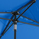 A blue Lancaster Table & Seating square umbrella with black poles.