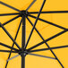 A close up of a yellow Lancaster Table & Seating umbrella with black poles.