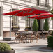 A patio with tables and chairs under red Lancaster Table & Seating cantilever umbrellas.