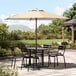 A Lancaster Table & Seating woodgrain umbrella over a table and chairs on a stone patio.