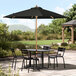 A Lancaster Table & Seating black umbrella on a table with chairs on a patio.