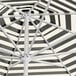 A close up of a black and white striped Lancaster Table & Seating umbrella over a white background.