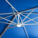 A close up of a blue Lancaster Table & Seating cantilever umbrella with a metal frame and white light fixture.