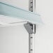 A white shelf with metal brackets attached to it inside an Avantco glass door merchandiser freezer.