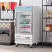 An Avantco swing glass door freezer with shelves holding ice cream containers.
