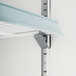 A white shelf with metal brackets attached to it.