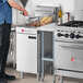 A man standing in a professional kitchen next to a white Wolf natural gas floor fryer.