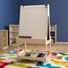 A Flash Furniture wooden mobile double-sided white board with a rolling tray on a colorful rug.