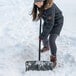 A woman using a Suncast snow shovel to clear snow.