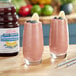 Two glasses of blueberry banana smoothie with straws on a counter.