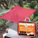 A red rectangular Xpose Safety shade sail over a patio.