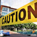 Yellow caution tape with black text reading "Caution" around a pool and a building.