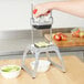 A person using a Vollrath Redco InstaCut 3.5 to cut celery into a white bowl.