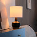 A Globe mid-century modern table lamp with a matte black and wood-toned base on a table.