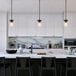 A kitchen with white cabinets and black counter tops with a Globe Modern Farmhouse Matte Black Pendant Light above the counter.