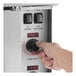 A person adjusting the timer knob on the control panel of a stainless steel electric convection oven.