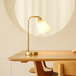 A Globe matte brass desk lamp on a wooden table.