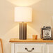 A Globe concrete table lamp on a dresser.