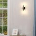 A Globe matte black and antique brass wall sconce on a white wall.