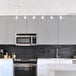 A modern kitchen with a Globe matte white adjustable height track light above white cabinets.