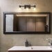A bathroom with a sink, mirror, and Globe Lofty Chic matte black vanity light with clear abstract shades.