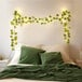 A bed with green pillows and Globe Juvenile Green Satin Ivy Vine LED String Lights.
