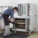A double deck full size electric convection oven with a person placing trays of baked goods inside.