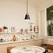 A Globe matte black and brass pendant light over a marble table and chairs.