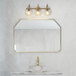 A Globe brass vanity light above a sink with a marble counter and a gold mirror.