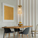 A matte brass rectangular globe pendant light over a wooden table with chairs and fruit.